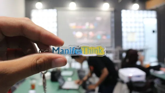 Gantungan kunci ManifesThink dipegang di ruang kegiatan